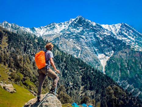 Man exploring breathtaking mountain scenery with snow-capped peaks under a clear blue sky.